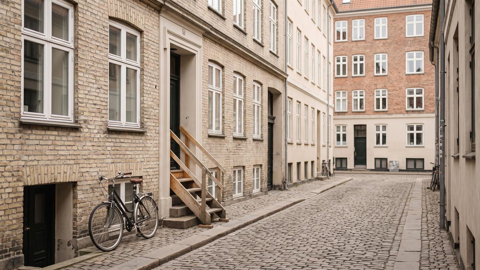 Small gade med ældre københavnske bygninger og brosten